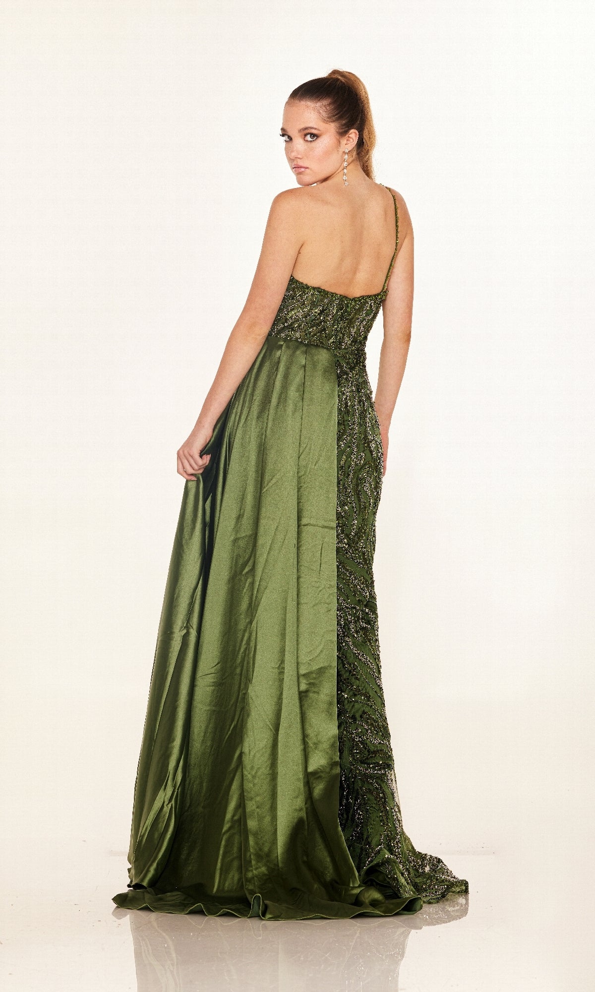 A woman models the Cecilia Couture C275, a green, floor-length, one-shoulder prom dress, standing with her back to the camera and head turned, set against a plain white background.